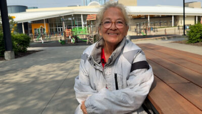 A woman with glasses and a white coat looks at the camera
