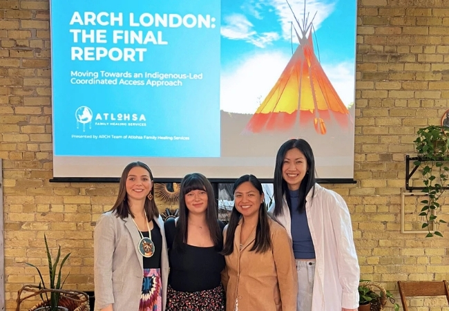 Team standing in front of the ARCH final report slide at the launch